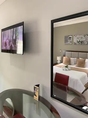 a mirror on a wall in a bedroom with a bed at The Pillows Suite in Pretoria