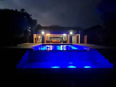 a swimming pool with blue lights in front of a house at No 16 Elements - 5 Bedroom Beauty in Moheme