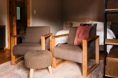a living room with two chairs and a bed at Zwakala River Retreat in Haenertsburg