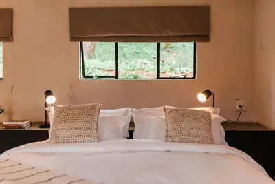 a bedroom with a bed with two pillows and a window at Zwakala River Retreat in Haenertsburg