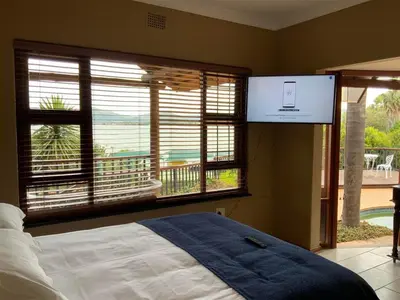 a bedroom with a bed and a large window at Marina Views Guesthouse in Hartbeespoort