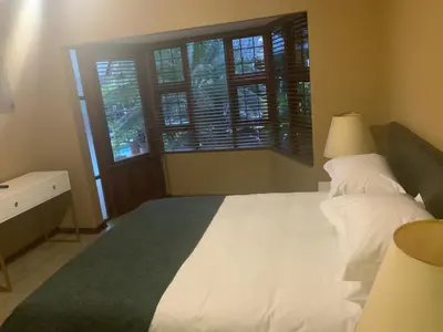 a bedroom with a large white bed and a window at Marina Views Guesthouse in Hartbeespoort