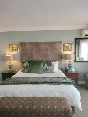 a bedroom with a large bed with a brown ottoman at 131 on Herbert Baker Boutique Hotel in Pretoria