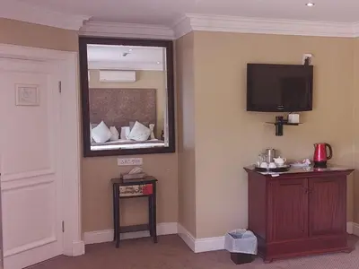 a room with a mirror and a tv on the wall at 131 on Herbert Baker Boutique Hotel in Pretoria