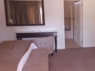 a bedroom with a bed and a mirror and a sink at 131 on Herbert Baker Boutique Hotel in Pretoria