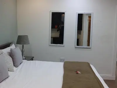 a bedroom with a white bed and two mirrors at 131 on Herbert Baker Boutique Hotel in Pretoria