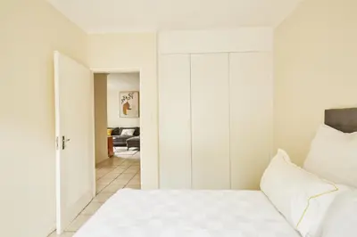 a white bedroom with a bed and a closet at Beautiful Two Bedroom Appartment In Hatfield in Pretoria