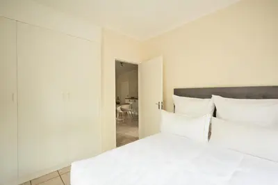 a white bed with white pillows in a bedroom at Beautiful Two Bedroom Appartment In Hatfield in Pretoria
