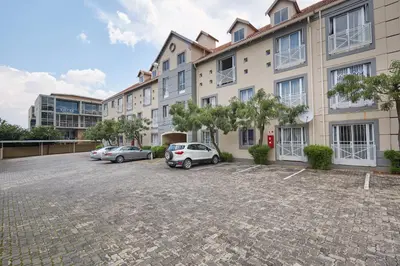 a parking lot with two cars parked in front of a building at Beautiful Two Bedroom Appartment In Hatfield in Pretoria