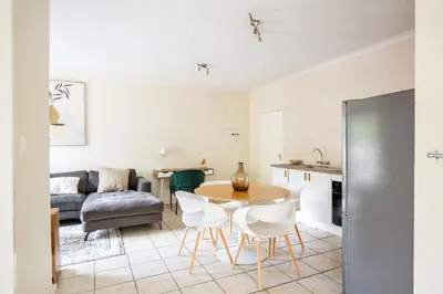 a kitchen and living room with a table and chairs at Beautiful Two Bedroom Appartment In Hatfield in Pretoria