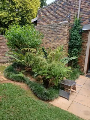 a bench sitting in a garden next to a brick wall at Green Scape Flatlet in Pretoria