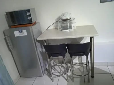 a small kitchen with a table and two bar stools at Green Scape Flatlet in Pretoria