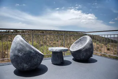 two large rocks and a bench on a balcony at Elements Sunrise Bush Lodge in Bela-Bela