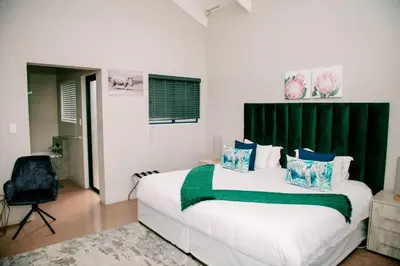 a bedroom with a large bed with a green headboard at Elements Sunrise Bush Lodge in Bela-Bela
