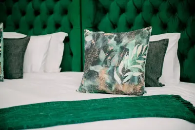 a bed with a green pillow on it at Elements Sunrise Bush Lodge in Bela-Bela
