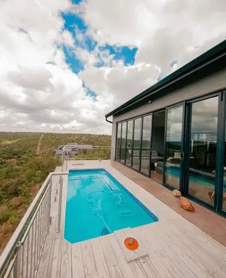 a swimming pool on the deck of a house at Elements Sunrise Bush Lodge in Bela-Bela