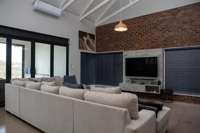 a living room with a large couch and a television at Elements Sunrise Bush Lodge in Bela-Bela