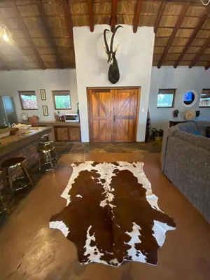 a living room with a cow rug on the floor at Livingstone Bush Lodge, Mabalingwe in Bela-Bela