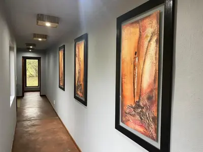 a hallway with several paintings on the wall at Livingstone Bush Lodge, Mabalingwe in Bela-Bela