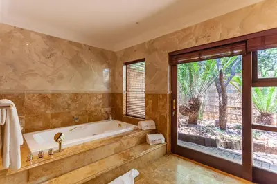 a bathroom with a tub and a large window at Lejwe La Metsi Private Reserve in Bela-Bela