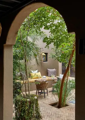 an archway with a table and chairs in a garden at Ukuthula House in Hectorspruit