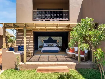 a master bedroom with a bed and a balcony at Ukuthula House in Hectorspruit