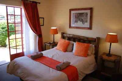 a bedroom with a bed with orange pillows at Journey's Inn Africa Guest Lodge in Kempton Park