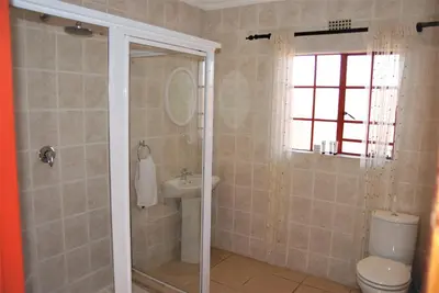 a bathroom with a shower and a toilet and a sink at Journey's Inn Africa Guest Lodge in Kempton Park
