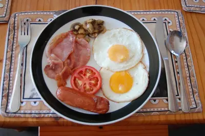 a plate of breakfast food with eggs sausage and bacon at Journey's Inn Africa Guest Lodge in Kempton Park