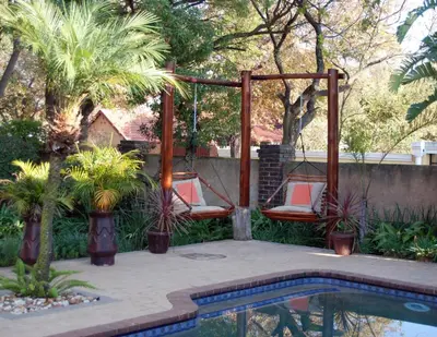 a patio with two chairs and a swing by a pool at Journey's Inn Africa Guest Lodge in Kempton Park