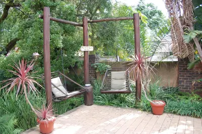 a pergola with two chairs in a garden at Journey's Inn Africa Guest Lodge in Kempton Park