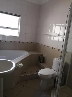 a bathroom with a tub and a toilet and a sink at Palm View Guest House in Pretoria