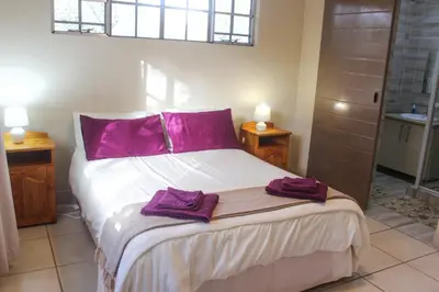 a bedroom with a bed with purple towels on it at Nature Cottage in Marloth Park