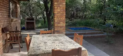 a table and chairs with a table and a pool at Nature Cottage in Marloth Park