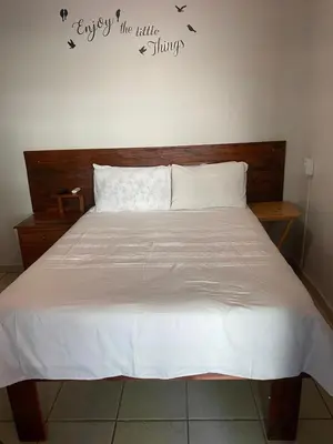 a bed with white sheets and a wooden head board at liam travel inn in Nelspruit