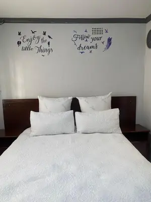 a bedroom with a bed with white sheets and butterflies on the wall at liam travel inn in Nelspruit