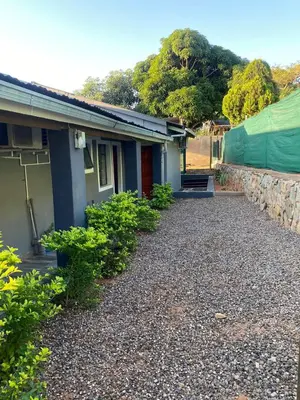 a house with a gravel driveway next to a building at liam travel inn in Nelspruit