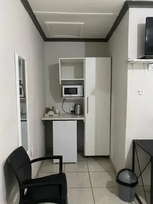 a small kitchen with a microwave and a chair at liam travel inn in Nelspruit