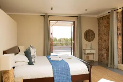 a bedroom with a bed and a large window at Vetho Farmhouse Dullstroom in Dullstroom