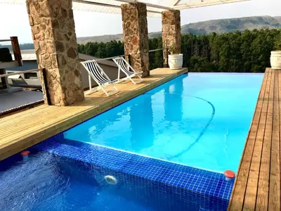 a pool with a deck and chairs on the side of a house at Vetho Farmhouse Dullstroom in Dullstroom