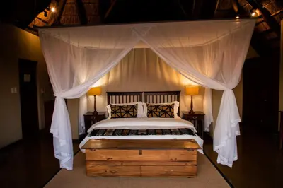 a bedroom with a canopy bed with two lamps at Nungubane Game Lodge in Welgevonden Game Reserve
