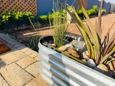 a metal planter with plants and rocks in it at Ko-Khoneng Guest house in Lebowakgomo