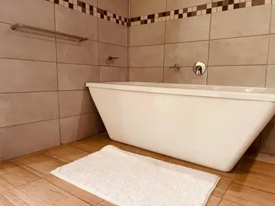 a bathroom with a white tub and a white rug at Ko-Khoneng Guest house in Lebowakgomo