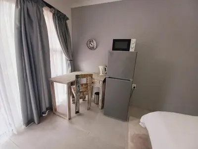 a small kitchen with a table and a refrigerator at Lime Court Three in Pretoria