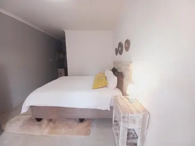a bedroom with a bed with white sheets and a table at Lime Court Three in Pretoria