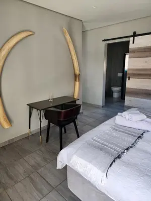 a bedroom with a bed and a desk with a piano at Lloyds - 3 in Ermelo