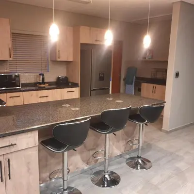 a kitchen with a counter with four bar stools at Lloyds - 3 in Ermelo
