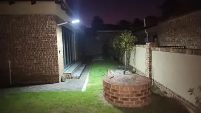 a backyard at night with a brick wall at Lloyds - 3 in Ermelo
