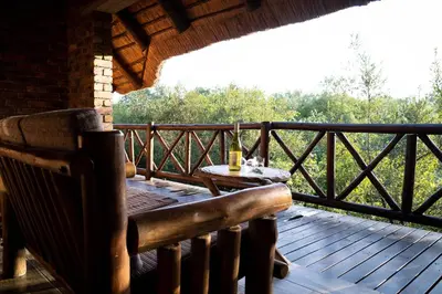 a wooden porch with a table on a deck at Jabulani Bushhouse - Marlothpark in Marloth Park