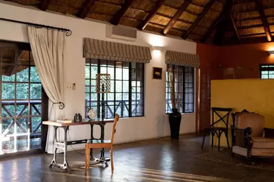 a room with a table and chairs and windows at Jabulani Bushhouse - Marlothpark in Marloth Park